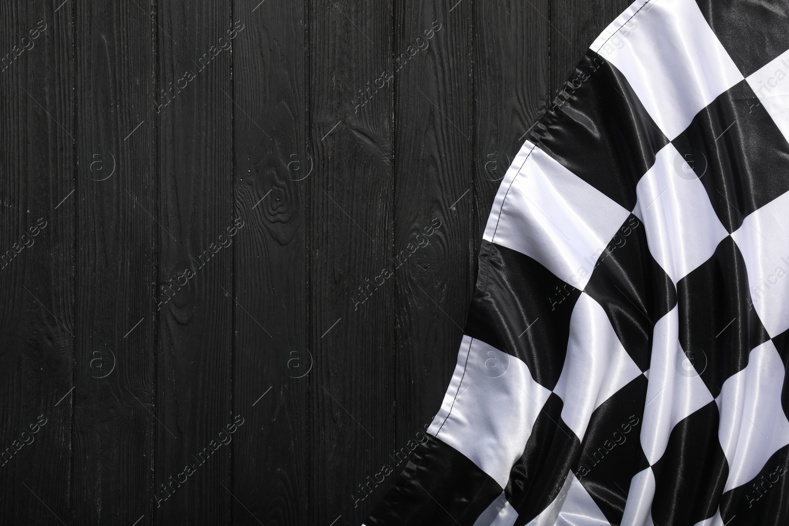 Photo of Checkered flag on black wooden table, top view. Space for text