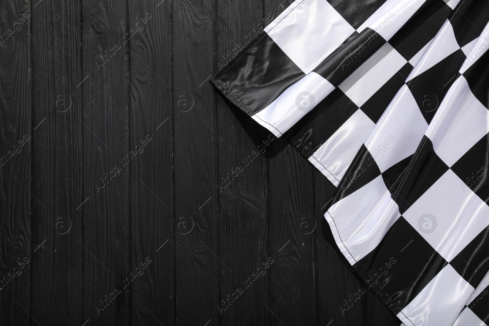 Photo of Checkered flag on black wooden table, top view. Space for text