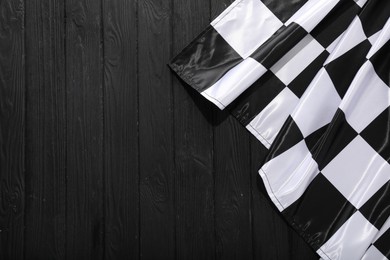 Photo of Checkered flag on black wooden table, top view. Space for text