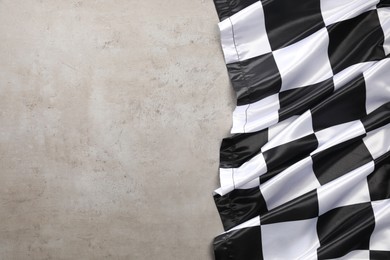 Photo of Checkered flag on grey table, top view. Space for text