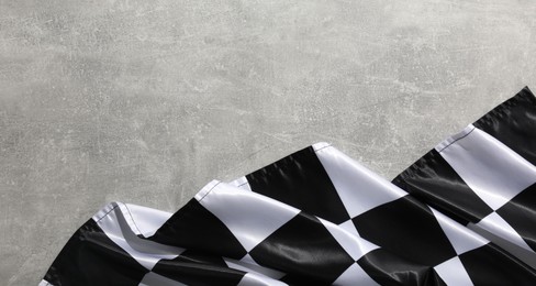 Photo of Checkered flag on grey table, top view. Space for text