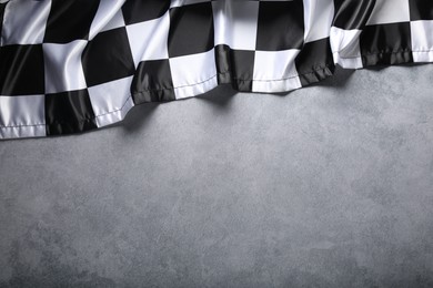 Photo of Checkered flag on grey table, top view. Space for text