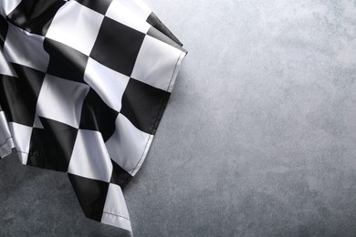 Photo of Checkered flag on grey table, top view. Space for text