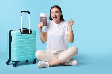 Photo of Woman with ticket, passport, and suitcase on light blue background