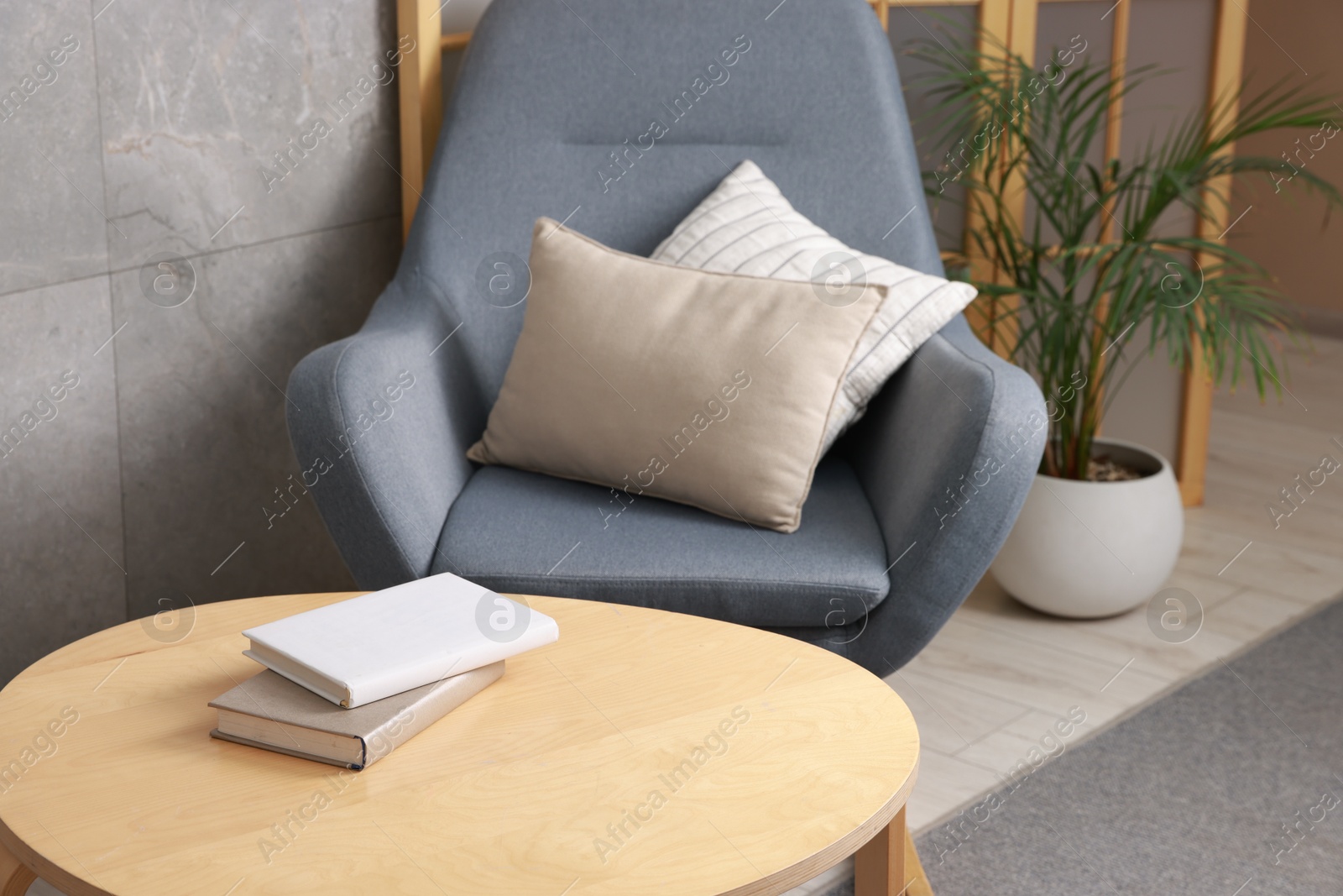 Photo of Stylish coffee table with books and rocking chair at home