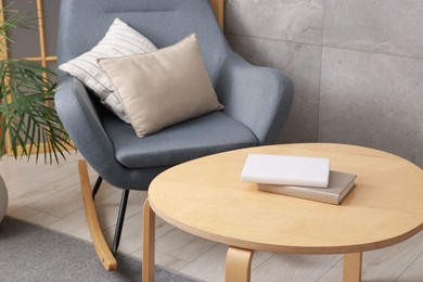 Photo of Stylish coffee table with books and rocking chair at home