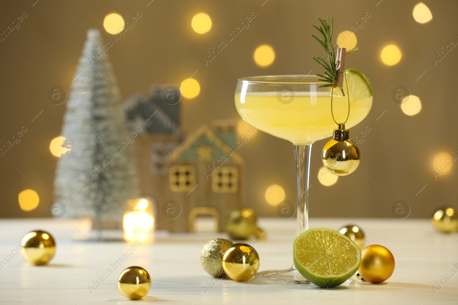 Photo of Tasty Christmas cocktail in glass and decor on white table against dark beige background with blurred lights. Space for text