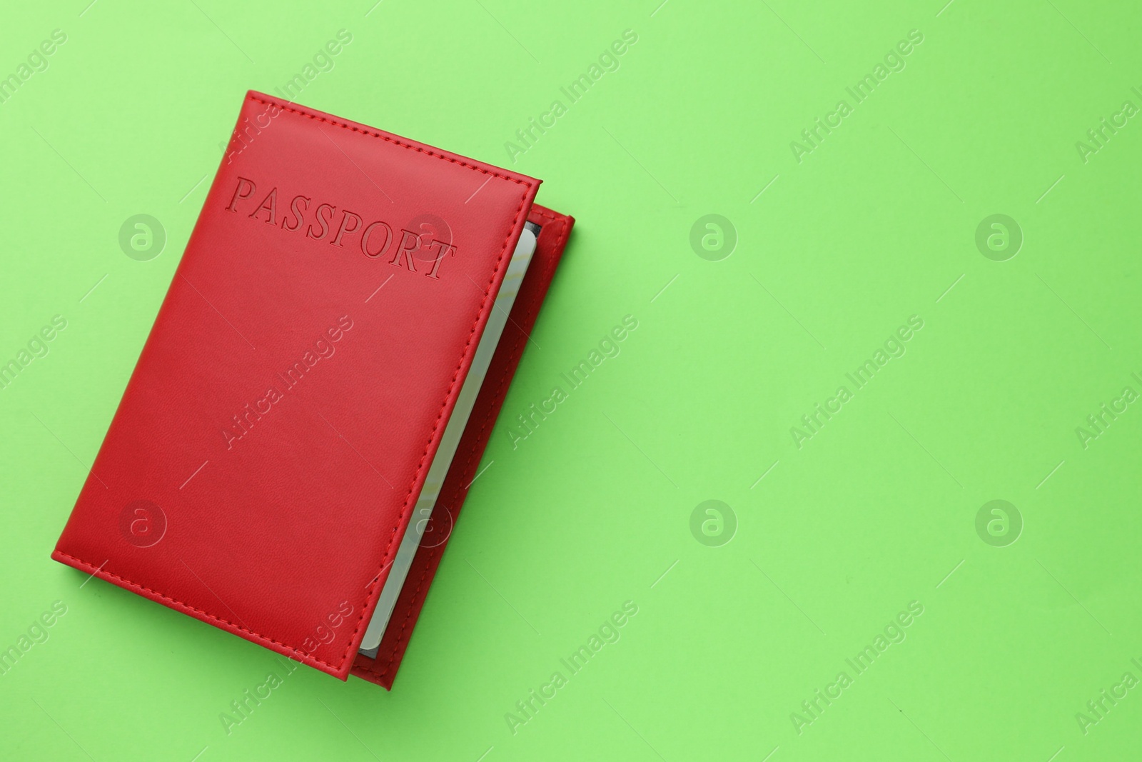 Photo of Passport in red cover on green background, top view. Space for text