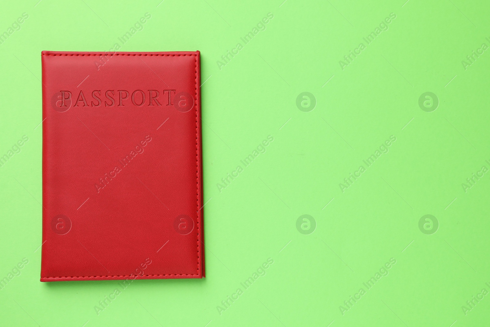 Photo of Passport in red cover on green background, top view. Space for text