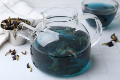 Photo of Delicious butterfly pea flower tea on white tiled table, closeup