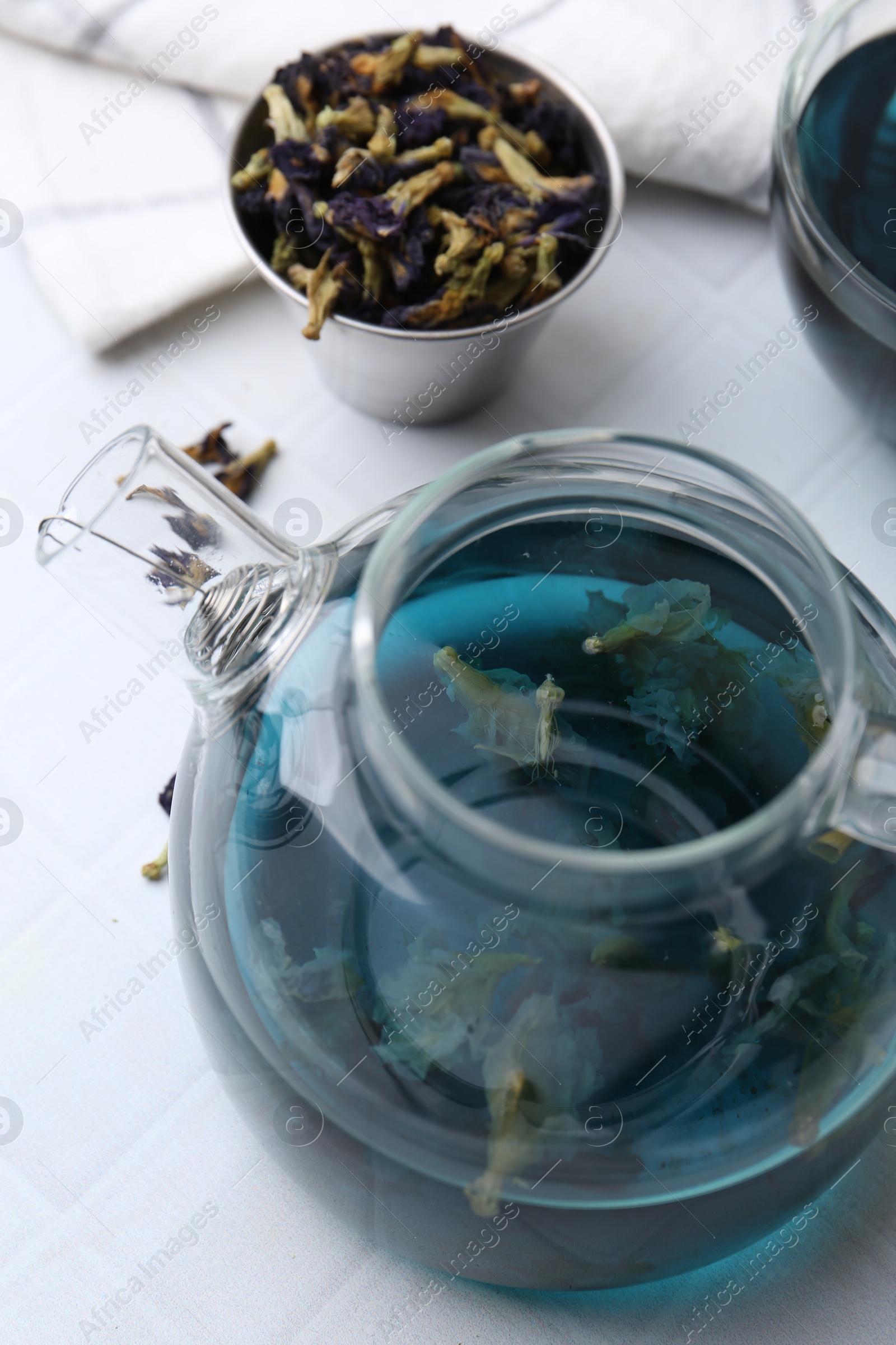 Photo of Delicious butterfly pea flower tea on white tiled table, closeup