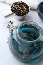 Delicious butterfly pea flower tea on white tiled table, closeup