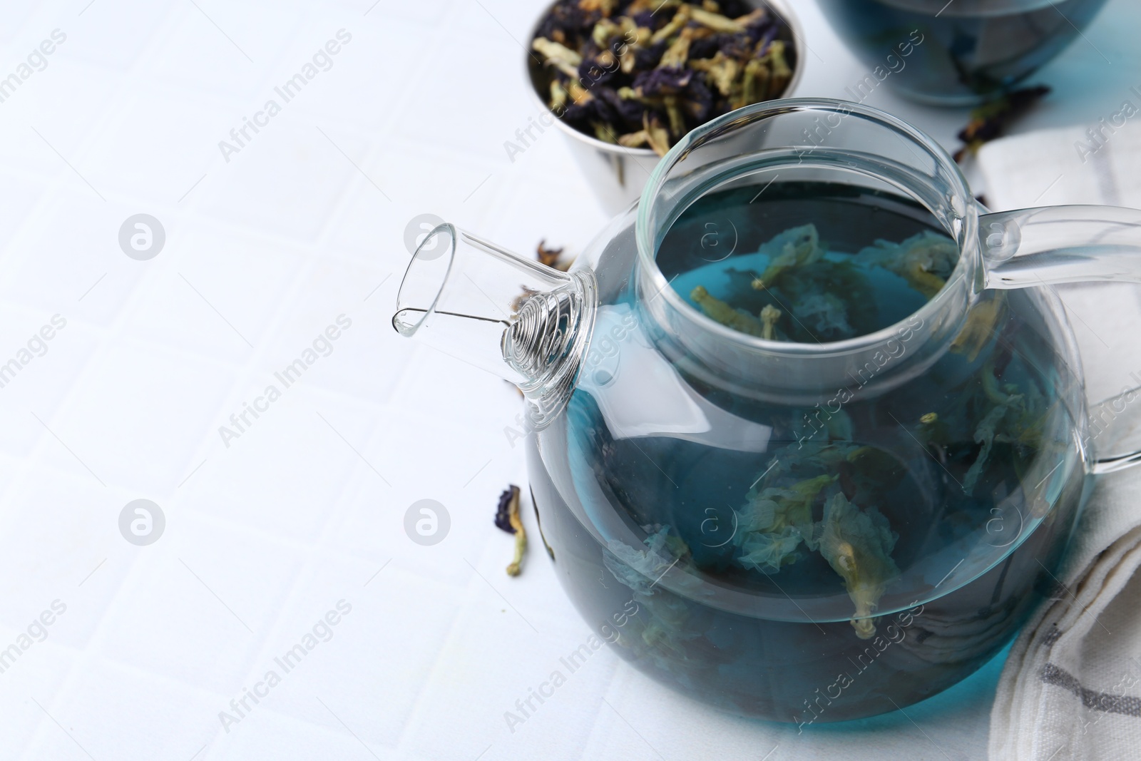 Photo of Delicious butterfly pea flower tea on white tiled table. Space for text