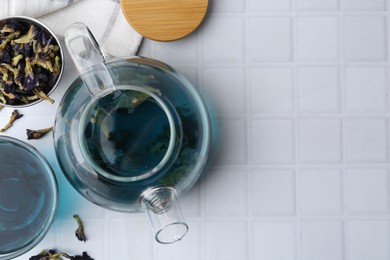 Photo of Delicious butterfly pea flower tea on white tiled table, flat lay. Space for text