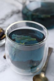 Photo of Delicious butterfly pea flower tea on white marble table, closeup