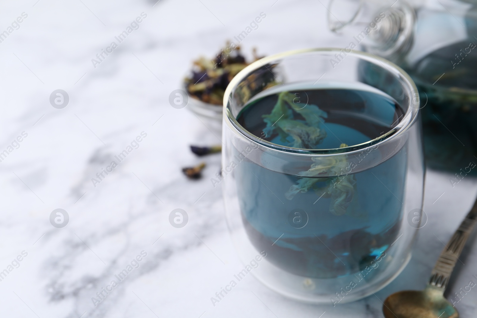 Photo of Delicious butterfly pea flower tea on white marble table, closeup. Space for text