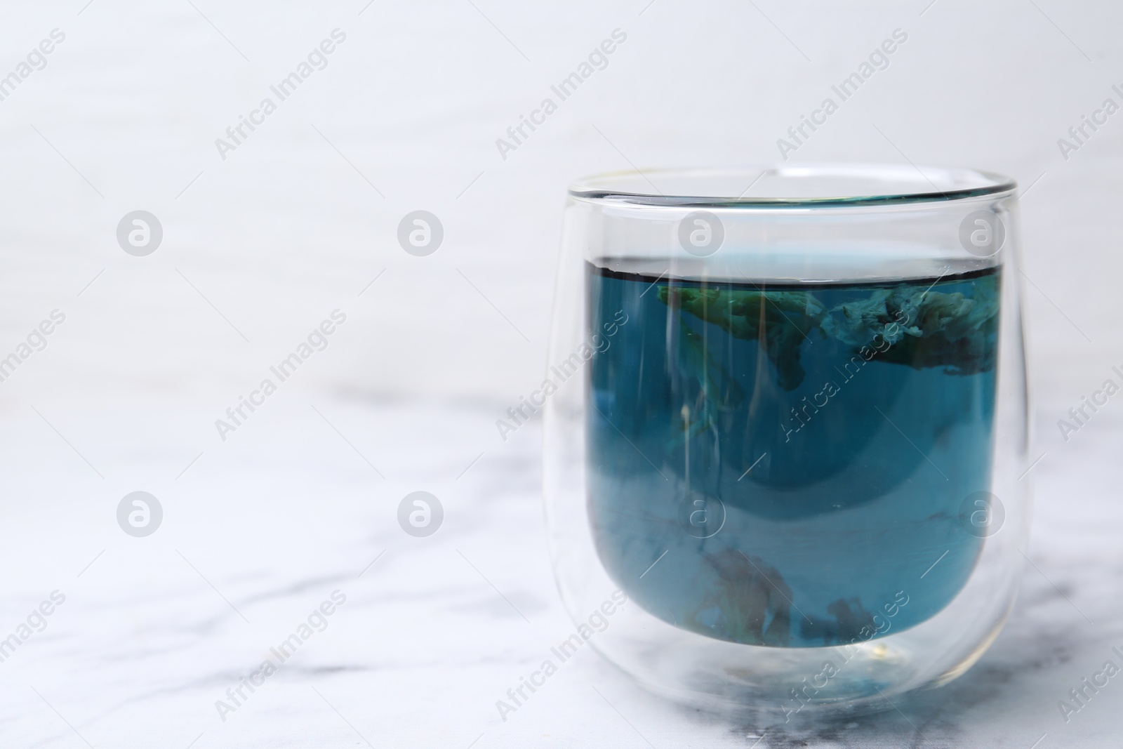 Photo of Delicious butterfly pea flower tea on white marble table. Space for text