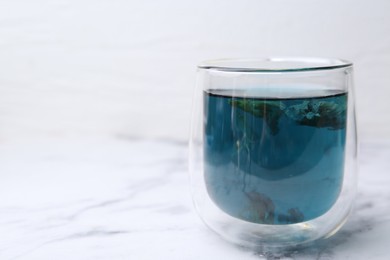 Photo of Delicious butterfly pea flower tea on white marble table. Space for text