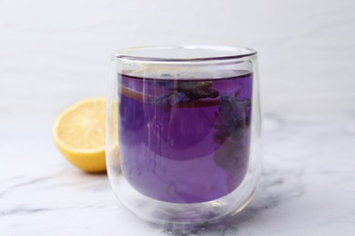 Photo of Delicious butterfly pea flower tea with lemon on white marble table