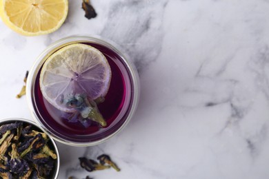 Photo of Delicious butterfly pea flower tea with lemon on white marble table, flat lay. Space for text