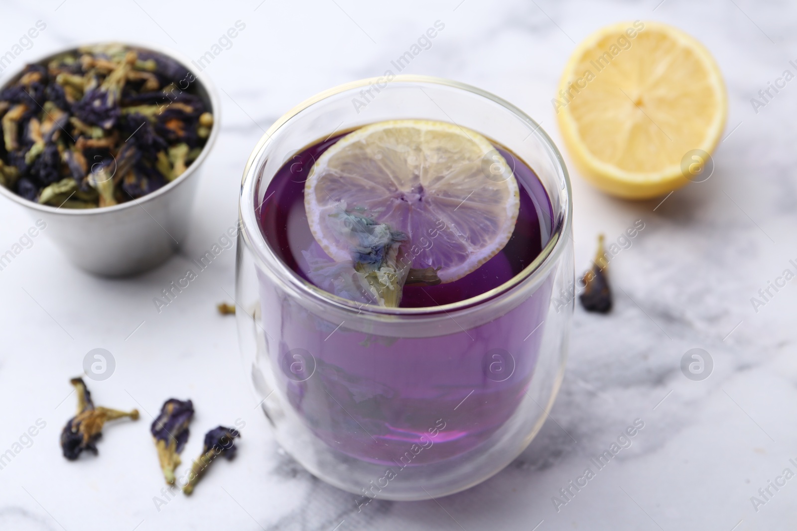 Photo of Delicious butterfly pea flower tea with lemon on white marble table, closeup