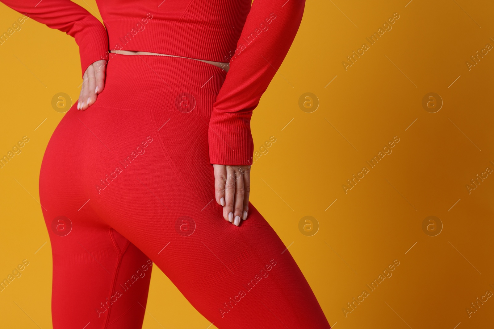 Photo of Woman in sportswear on orange background, closeup. Space for text