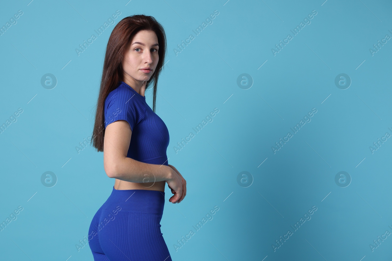 Photo of Woman in sportswear on light blue background, space for text