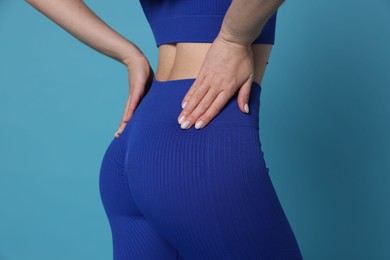 Photo of Woman in sportswear on light blue background, closeup