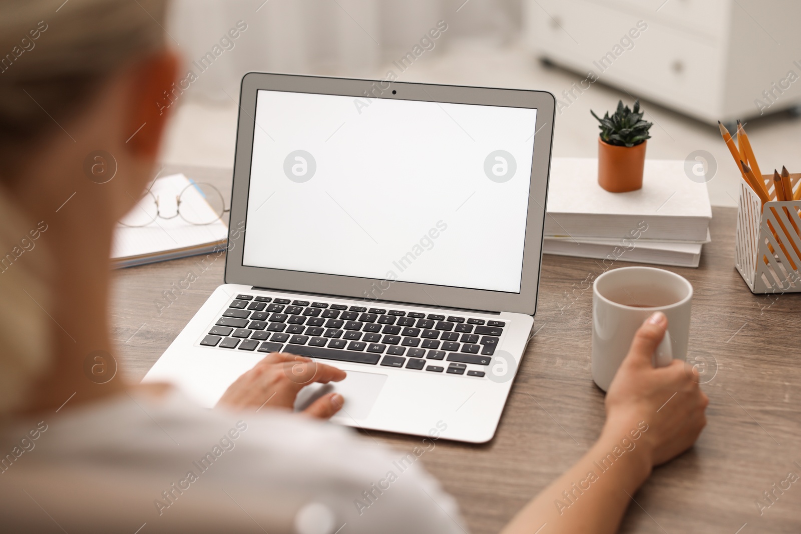 Photo of Woman working with laptop at wooden table in office, closeup. Mockup for design