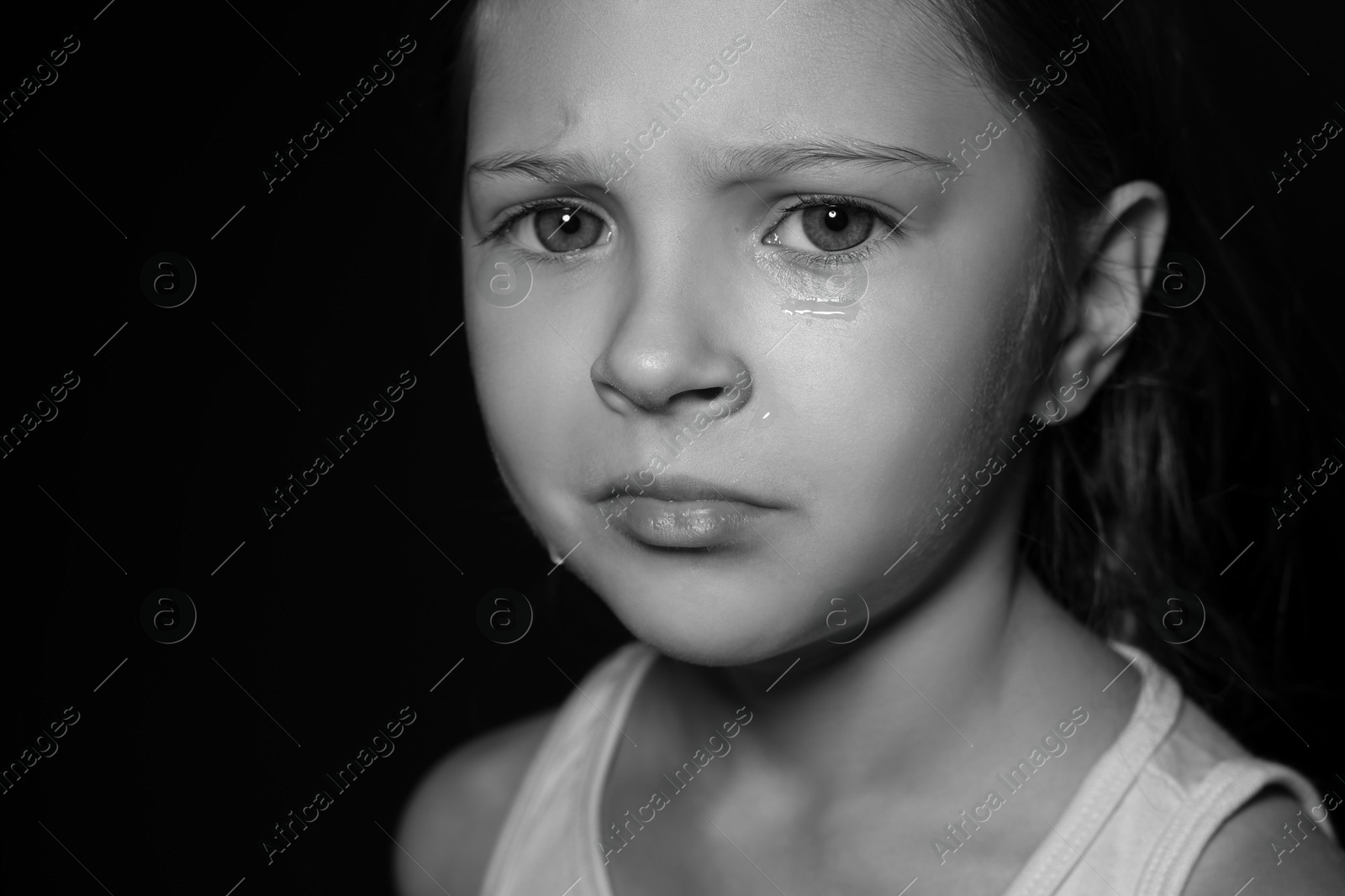 Photo of Orphanage concept. Sad girl on dark background. Black and white effect