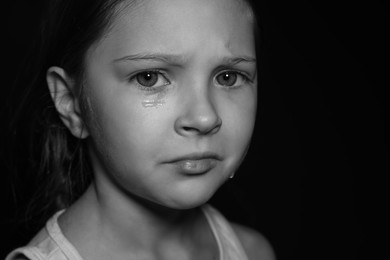 Photo of Orphanage concept. Sad girl on dark background. Black and white effect