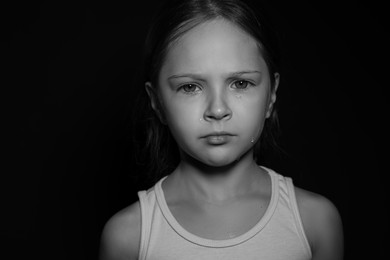 Orphanage concept. Sad girl on dark background. Black and white effect