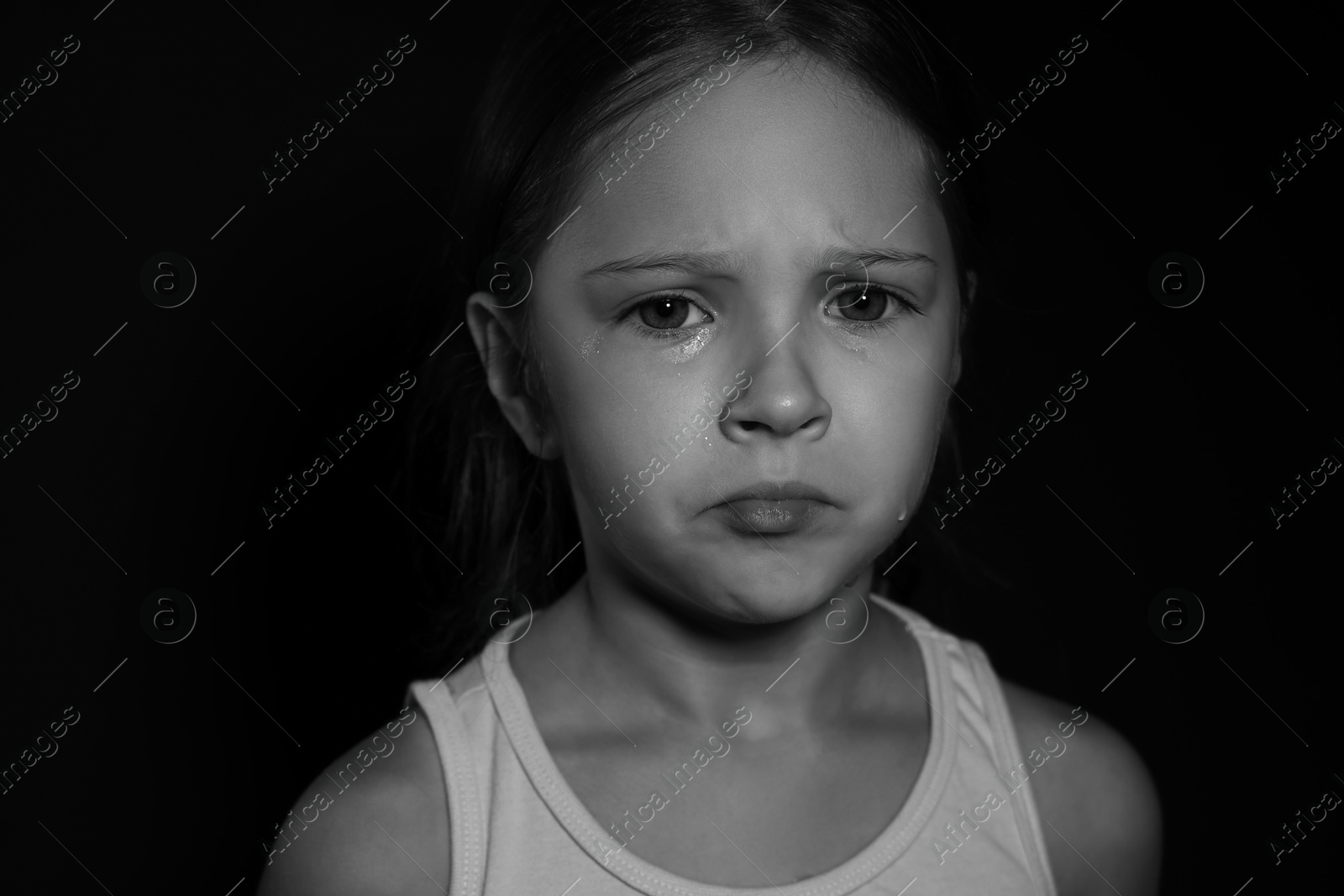 Photo of Orphanage concept. Sad girl on dark background. Black and white effect