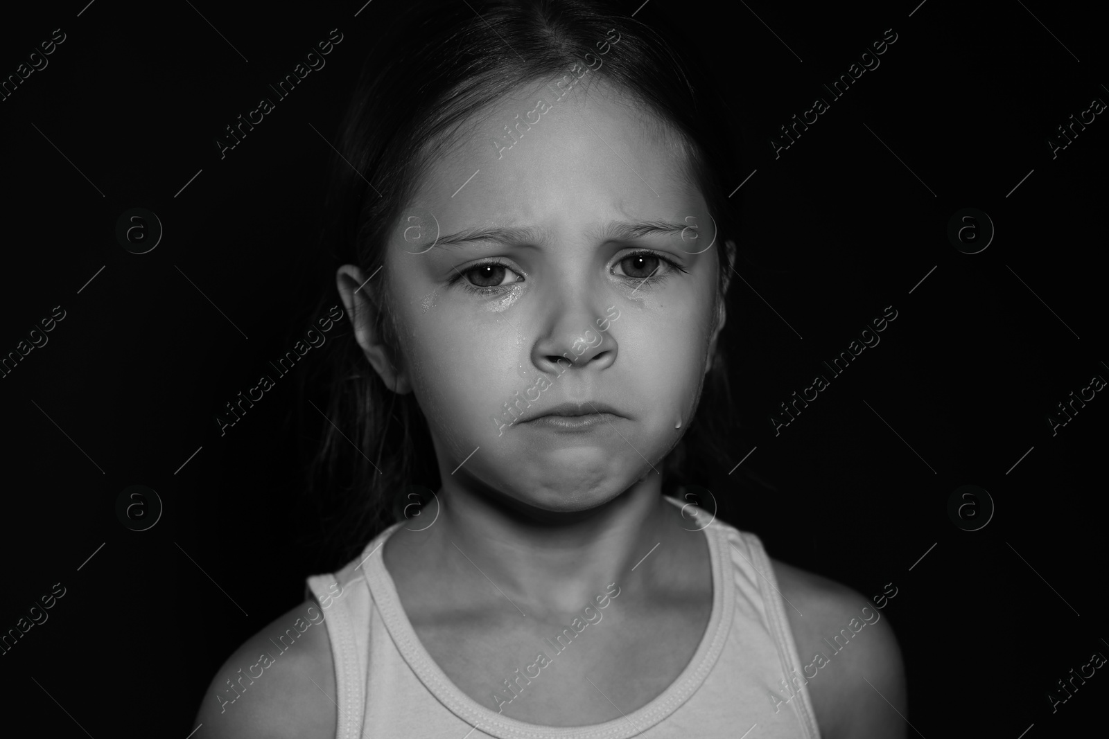 Photo of Orphanage concept. Sad girl on dark background. Black and white effect