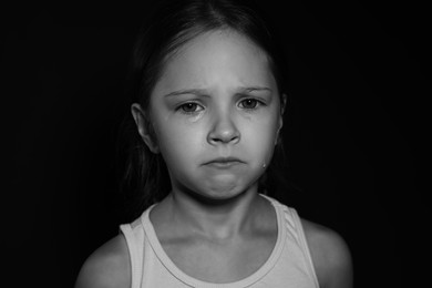 Orphanage concept. Sad girl on dark background. Black and white effect