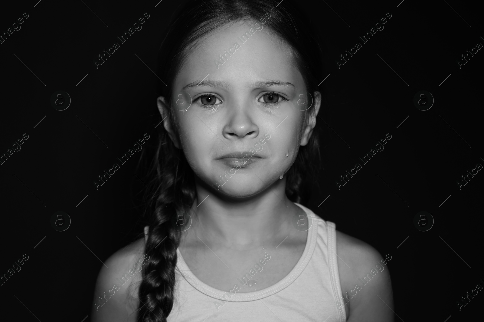 Photo of Orphanage concept. Sad girl on dark background. Black and white effect