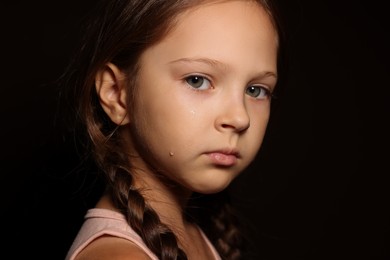 Photo of Orphanage concept. Sad girl on black background