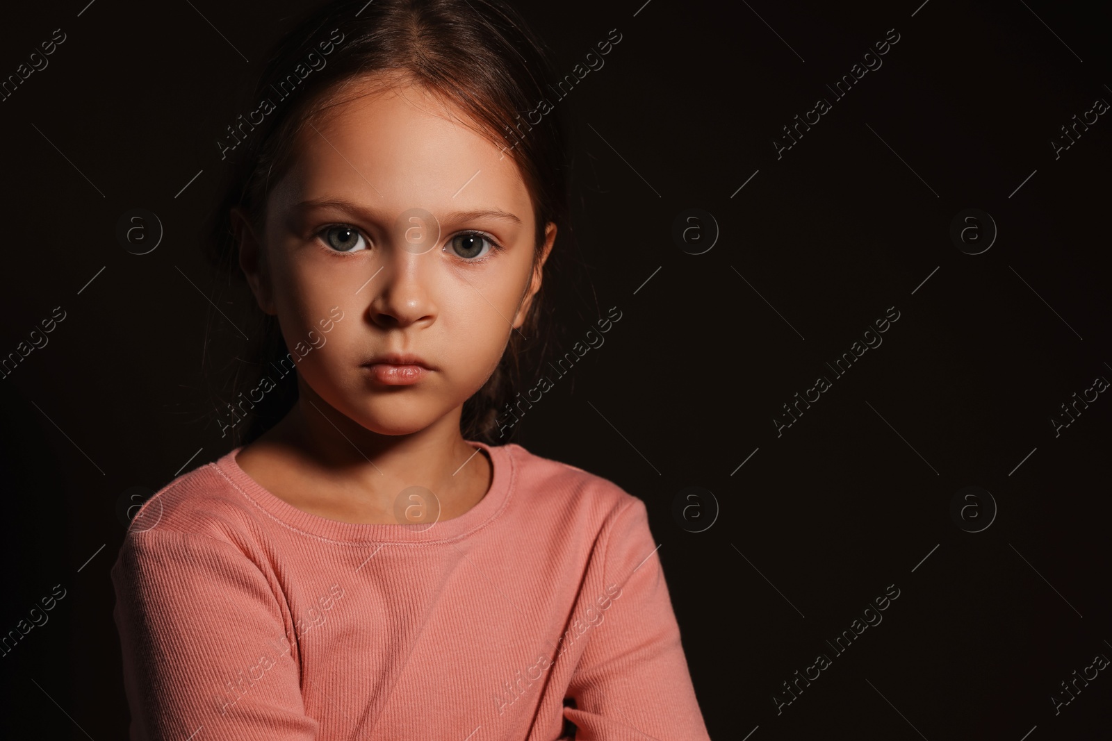 Photo of Orphanage concept. Sad girl on black background