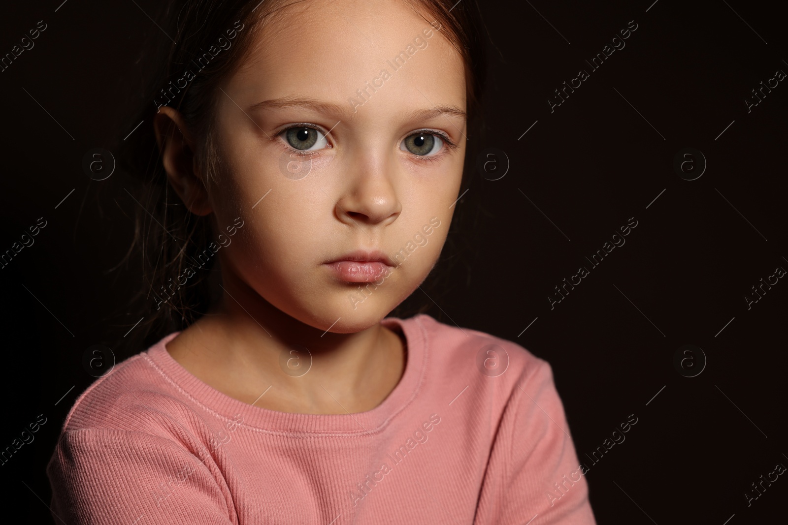 Photo of Orphanage concept. Sad girl on black background