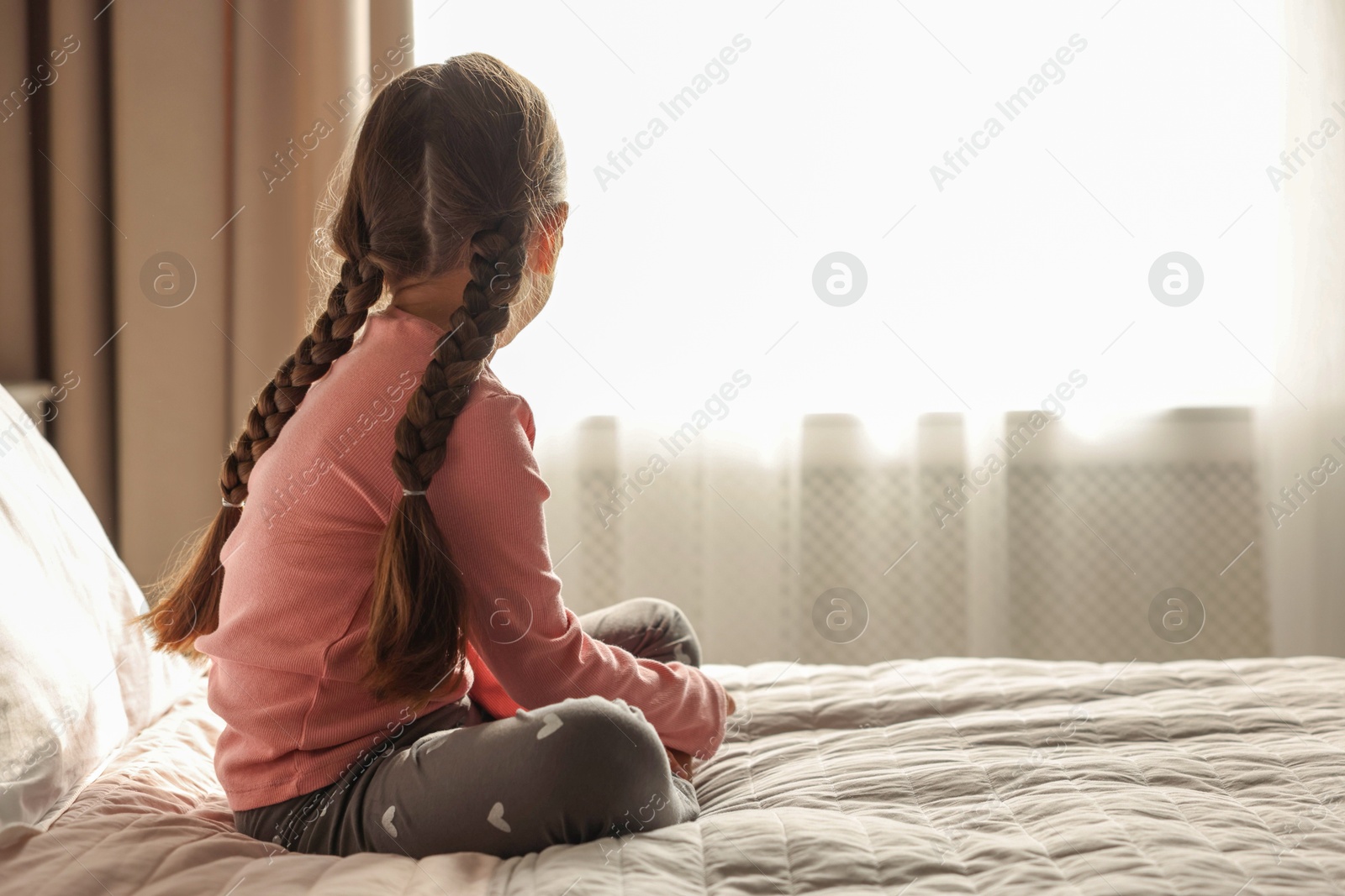 Photo of Orphanage concept. Girl on bed in room, back view