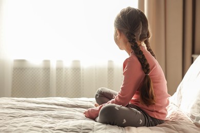 Photo of Orphanage concept. Girl on bed in room, back view