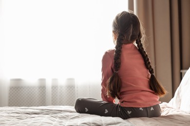 Photo of Orphanage concept. Girl on bed in room, back view