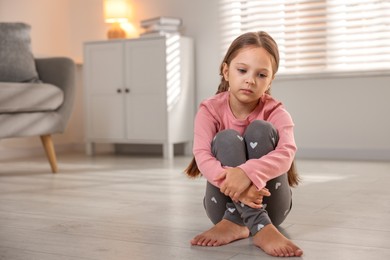 Photo of Orphanage concept. Sad girl sitting on floor indoors