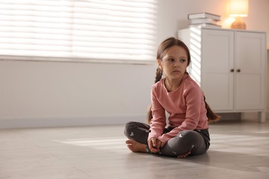 Photo of Orphanage concept. Sad girl sitting on floor indoors