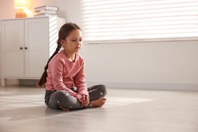 Orphanage concept. Sad girl sitting on floor indoors