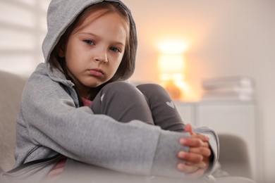 Photo of Orphanage concept. Sad girl sitting on sofa indoors