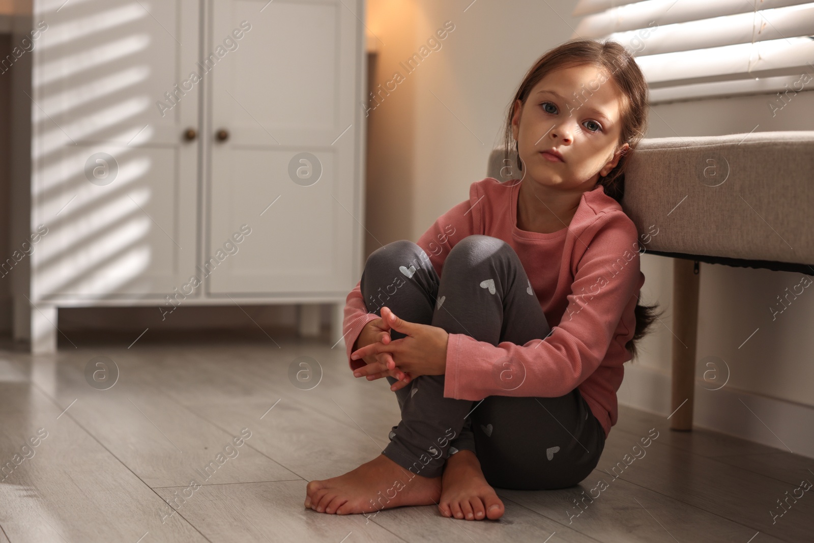 Photo of Orphanage concept. Sad girl sitting on floor indoors