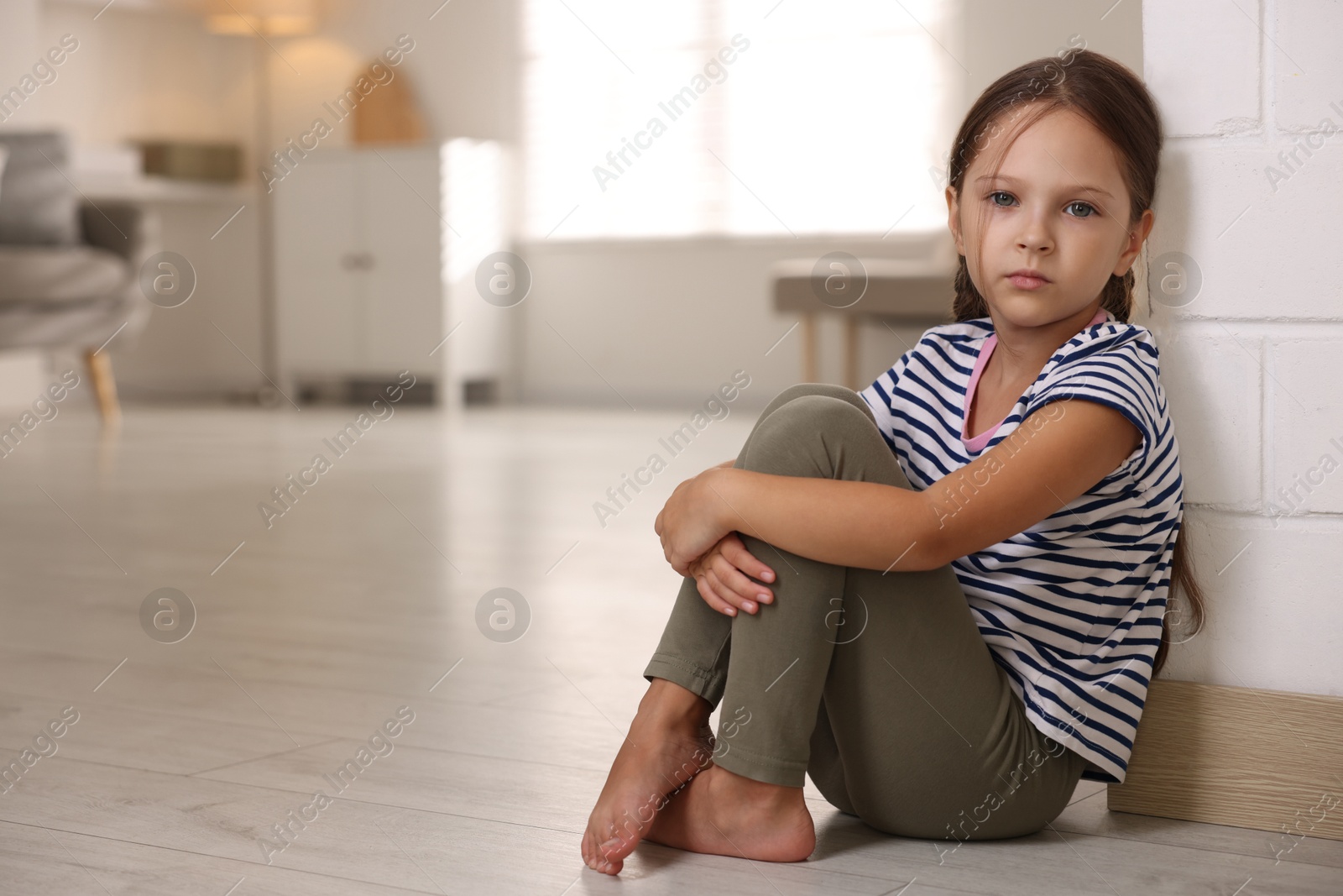 Photo of Orphanage concept. Sad girl sitting on floor indoors