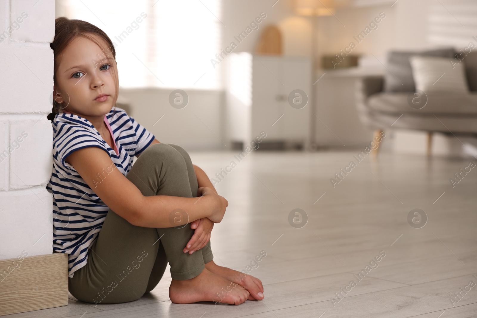 Photo of Orphanage concept. Sad girl sitting on floor indoors