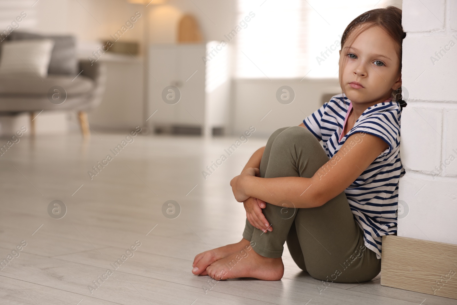 Photo of Orphanage concept. Sad girl sitting on floor indoors